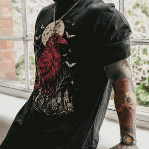 A man wearing the Crow medieval graphic t-shirt by inked 13 leaning against a window.